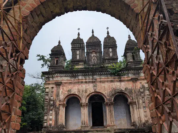 Old temples seen through a brick archway at Chilkigarh Rajbari